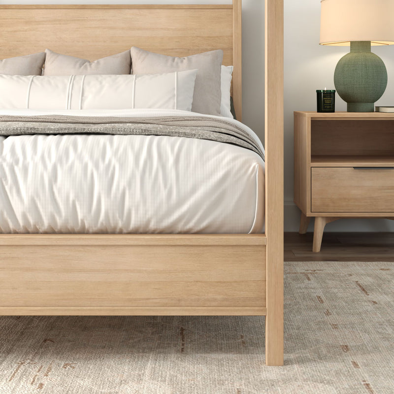 Light wood four-poster bed with white and beige bedding, mid-century nightstand, green ceramic lamp and neutral area rug