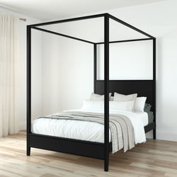 Modern black metal canopy four-poster bed with white bedding in a minimalist bedroom on light hardwood floor