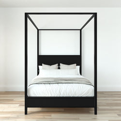 Minimalist black four-poster canopy bed with white bedding and neutral pillows on light hardwood floor in modern bedroom