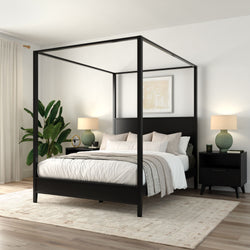 Modern black four-poster canopy bed in a minimalist neutral bedroom with white linens, beige throw, black nightstands, green table lamps, potted plant, area rug and light hardwood floors