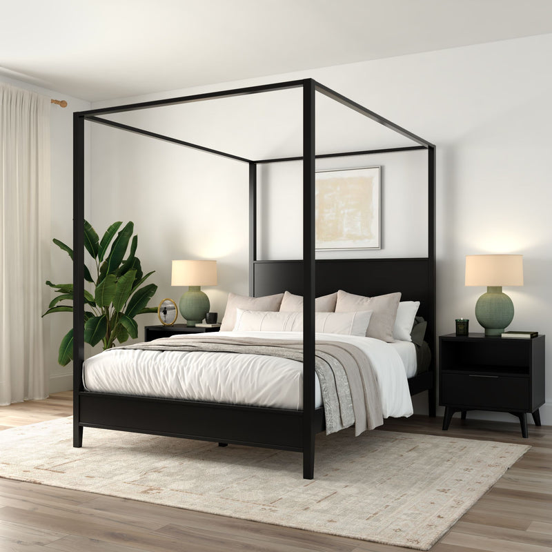 Modern black four-poster canopy bed in a minimalist neutral bedroom with white linens, beige throw, black nightstands, green table lamps, potted plant, area rug and light hardwood floors