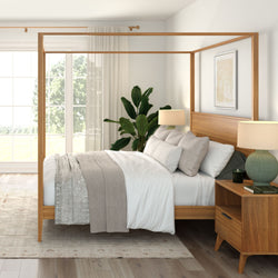 Cozy bedroom with wooden canopy bed, neutral bedding, and indoor plant by a large window.