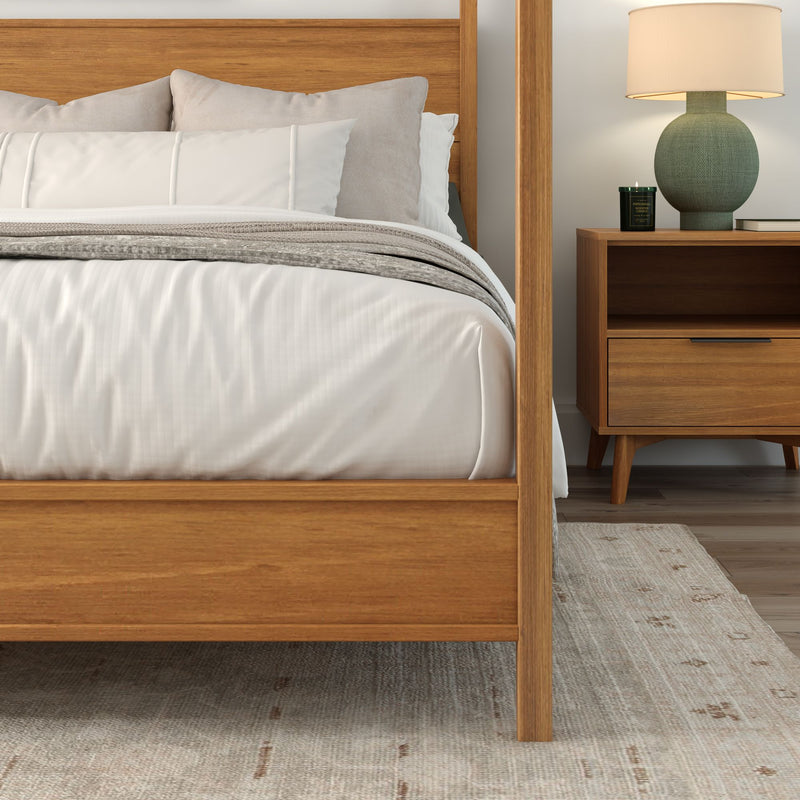 Cozy minimalist bedroom with wooden bed frame, neutral bedding, mid-century nightstand, green ceramic lamp and area rug.