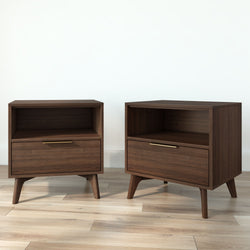 Pair of mid-century modern walnut nightstands with open shelf and single drawer, brass handles and tapered legs on light hardwood floor