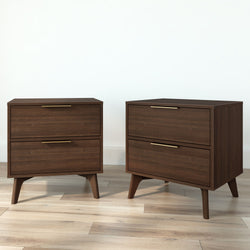 Pair of mid-century modern walnut two-drawer nightstands with brass handles and tapered wooden legs on light hardwood floor
