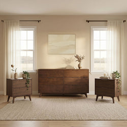 Mid-century modern bedroom with dark wood dresser and matching nightstands, sheer white curtains on twin windows, neutral wall art, decorative vases and woven area rug