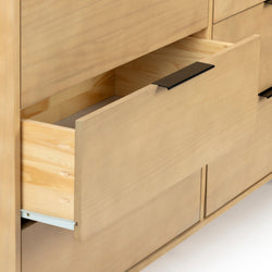 Light maple wooden dresser close-up with open drawer and sleek black handle, modern minimalist bedroom storage and furniture detail