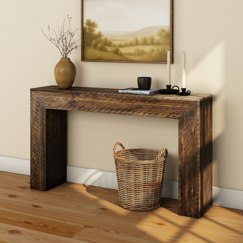Rustic wooden console table with decorative items, wicker basket, and painting in a cozy interior setting.