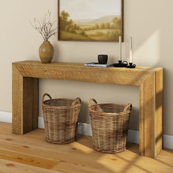 Rustic wooden console table with two woven wicker baskets underneath, neutral landscape wall art, ceramic vase with dried branches and black candle holders on hardwood floor