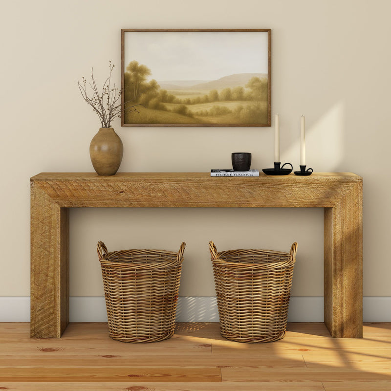 Rustic wooden console table in a neutral entryway with two woven wicker baskets underneath, ceramic vase with branches, black candle holders and framed landscape painting, modern farmhouse home decor