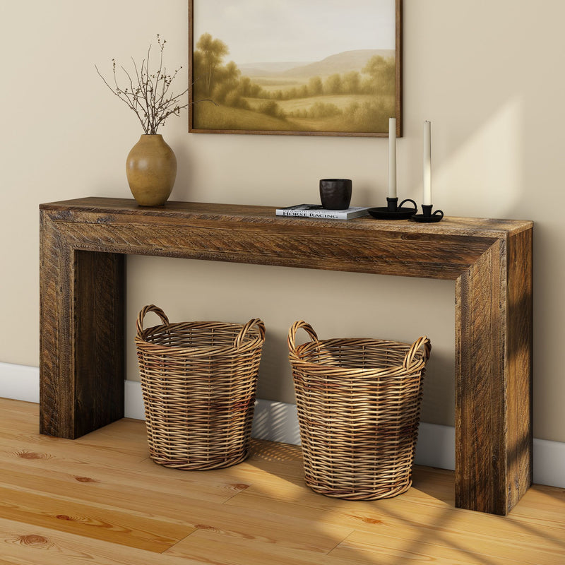 Rustic reclaimed wood console table with two woven wicker baskets, vase and candles in farmhouse entryway on hardwood floor