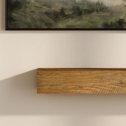 Floating rustic wooden wall shelf on beige wall beneath framed landscape painting, modern farmhouse living room decor