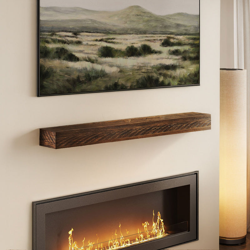 Reclaimed wood floating mantel shelf mounted above a modern recessed electric fireplace with landscape wall art and floor lamp, rustic living room decor