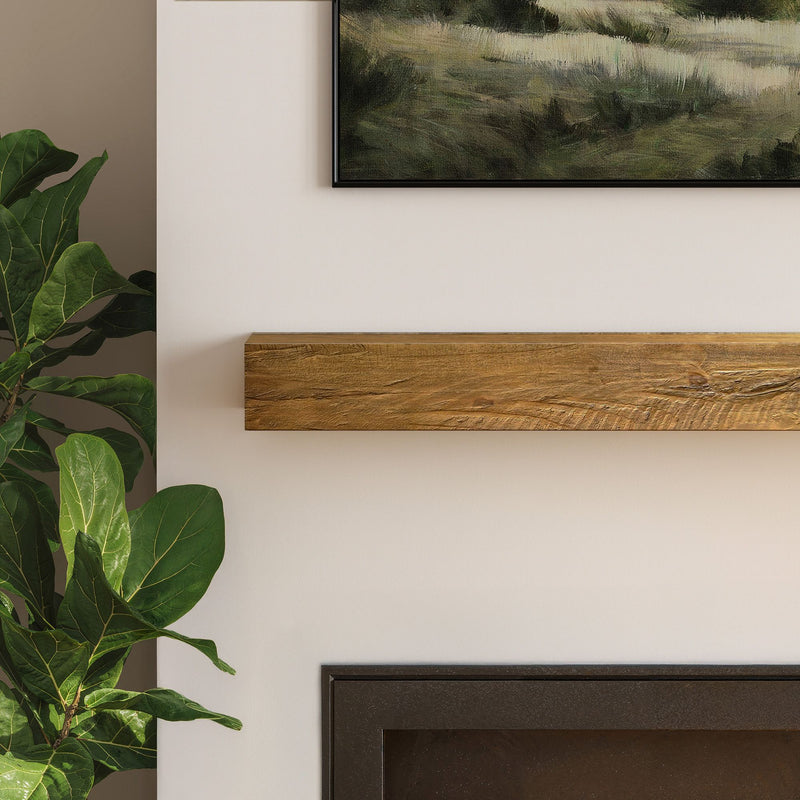 Modern living room close-up: rustic wood mantel above fireplace with framed landscape art and fiddle leaf fig plant on cream wall