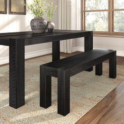 Modern black wooden dining table and bench with decorative vases on a textured rug in a bright room.