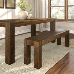 Rustic wooden dining table set with matching bench on textured area rug in bright dining room.