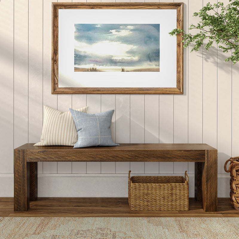 Modern rustic living room with wooden bench, decorative pillows, framed landscape art, and woven basket storage.