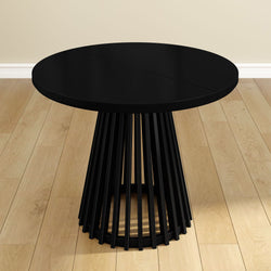 Round black modern dining table with slatted base on wood floor.
