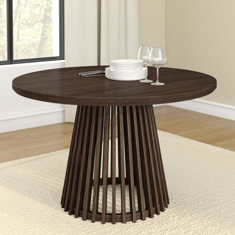 Round modern wooden dining table with elegant pedestal base, set with wine glasses and plates in a bright, stylish dining room.