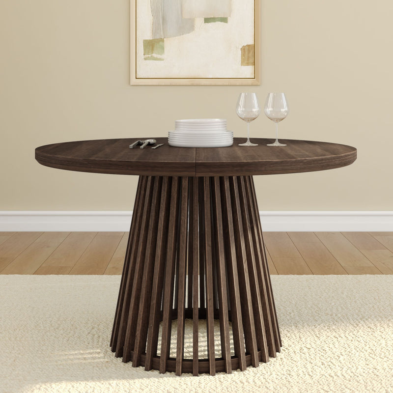 Modern round wooden dining table with unique slatted base design in a minimalist dining room setting.