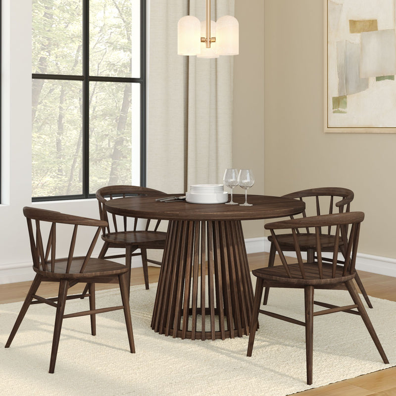 Modern dining room with round wooden table and chairs, white plates, glasses, and contemporary decor.