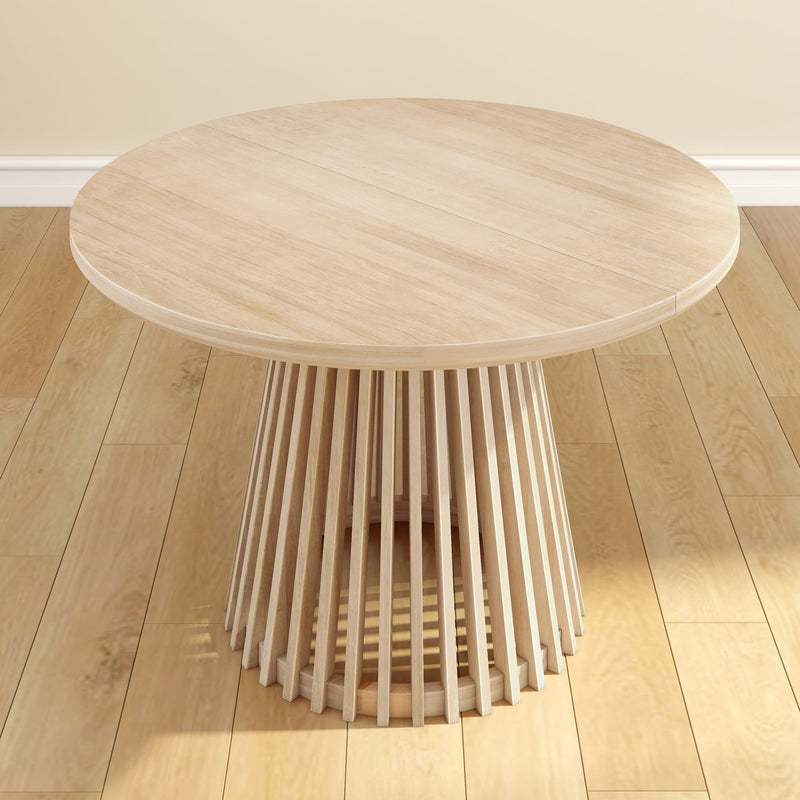 Round wooden dining table with modern slatted base on hardwood floor.