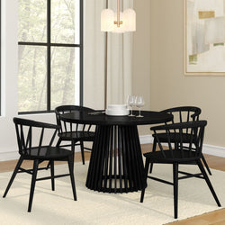 Modern dining room with a black round table and four chairs, elegant tableware and stylish pendant lighting.