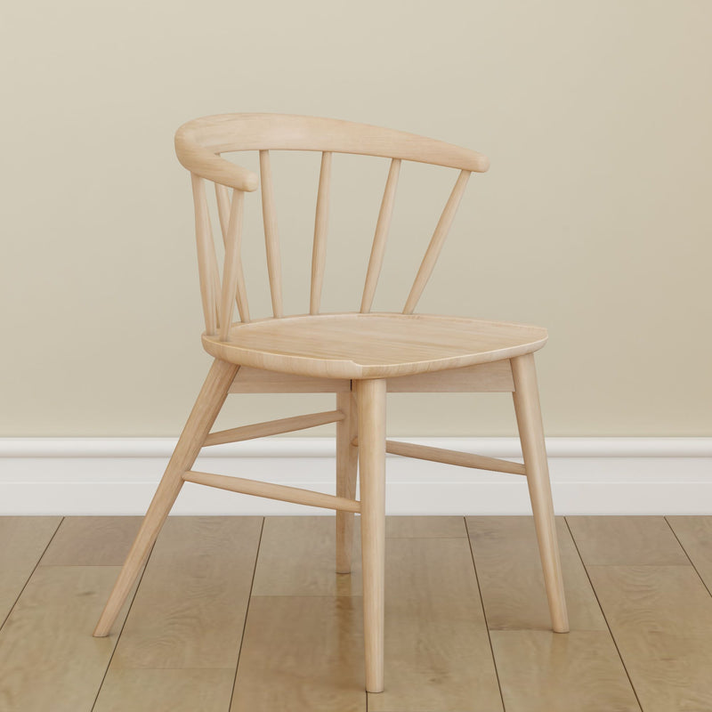 Minimalist wooden chair with a curved backrest on hardwood floor against a beige wall.