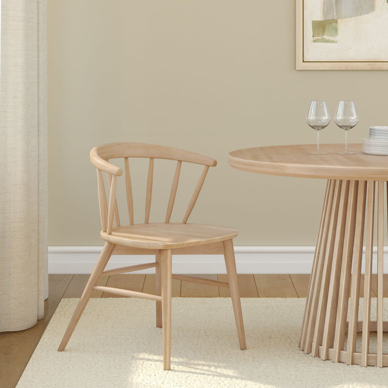Wooden dining chair and round table in minimalist room setting with beige walls.