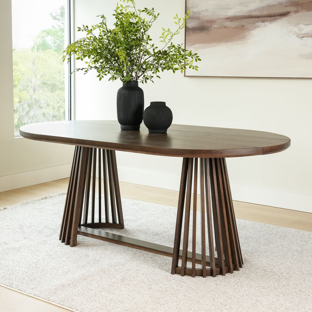 Modern oval wooden dining table with unique lattice base design featuring decorative black vases and green foliage, set on a neutral rug in a contemporary dining room.