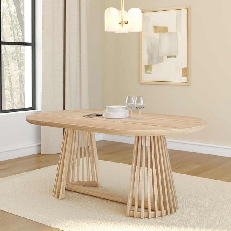 Modern light oak dining table with slatted pedestal base in neutral dining room, round extension table with wine glasses and stacked plates