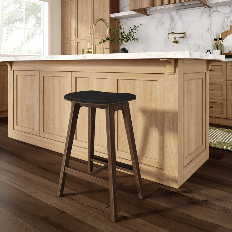 Modern farmhouse kitchen with light oak island and shaker cabinets, white marble countertop, brass faucet, dark-wood bar stool with black seat, potted greenery and wide-plank hardwood floors