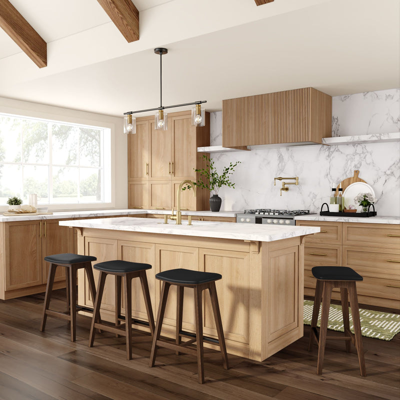 Modern farmhouse kitchen with white marble countertops, light oak cabinets, large island with four wood stools, brass faucet, pendant lighting and hardwood floors