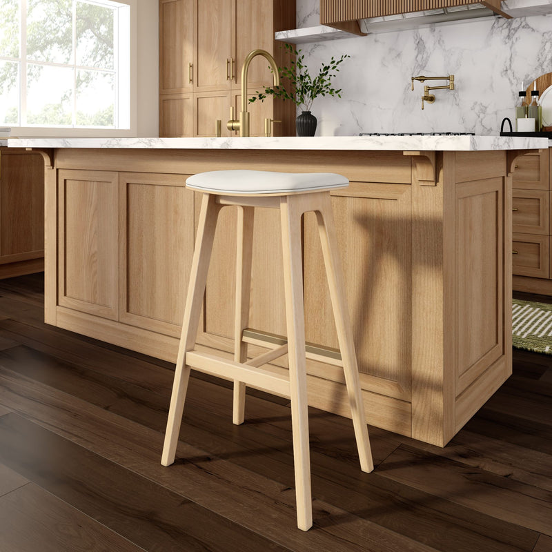 Wooden kitchen stool in a modern kitchen with oak island, marble countertop, and gold faucet.