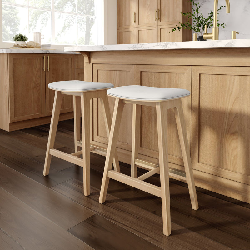 Two modern wooden bar stools with white seats in a kitchen with wooden cabinets and marble countertop.