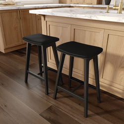 Pair of black backless counter stools with padded seats at a light oak kitchen island featuring a white marble countertop and dark hardwood floors