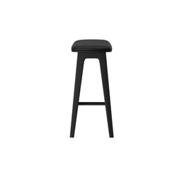 Front view of modern black bar stool with padded leather seat, tapered wooden legs and footrest on white background