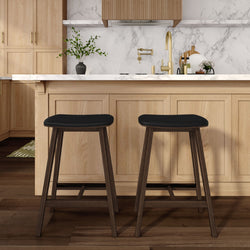 Modern kitchen island with two dark-wood bar stools, light oak cabinetry, white marble countertop and backsplash, brass faucet and hardwood floors