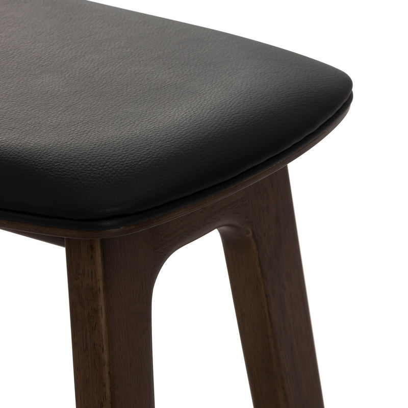 Close-up of black leather upholstered bar stool seat with dark walnut solid wood legs, modern minimalist kitchen counter stool