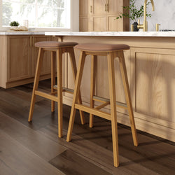 Two modern wooden bar stools with leather seats at a stylish kitchen island, highlighting contemporary kitchen design.