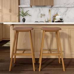 Modern kitchen with wooden bar stools, marble backsplash, and gold fixtures.