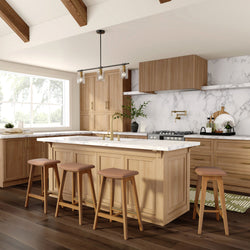 Bright modern farmhouse kitchen with light oak cabinets, white marble countertops and backsplash, large island with brass faucet, four wooden bar stools, pendant lighting and dark hardwood floors