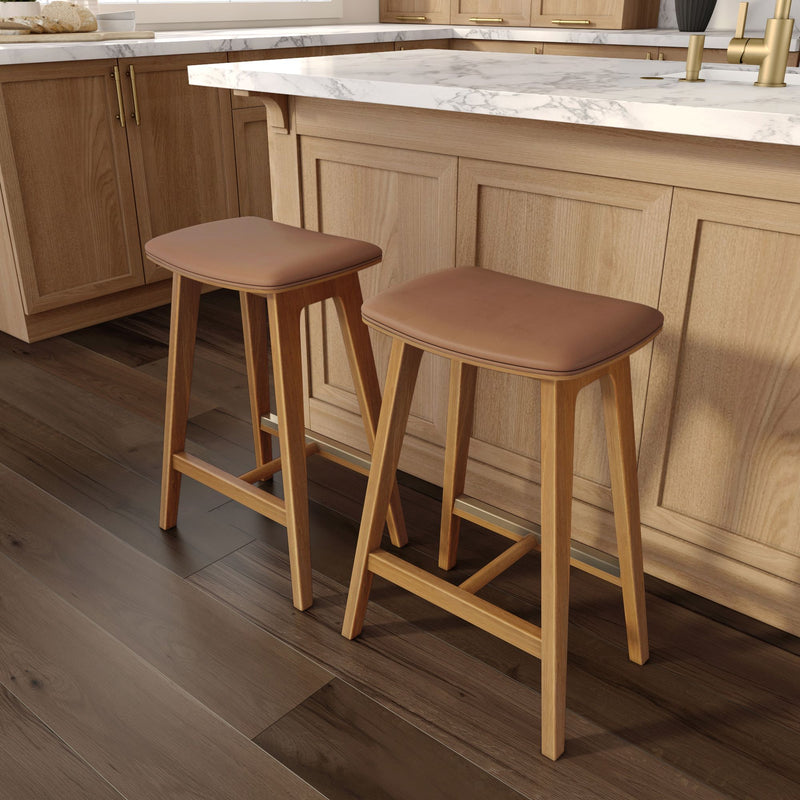 Contemporary kitchen breakfast bar with white marble countertop, light oak cabinets and two mid-century wooden bar stools with tan leather seats on dark hardwood floor