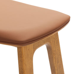 Close-up of tan leather padded seat and oak wood legs of mid-century modern bar stool