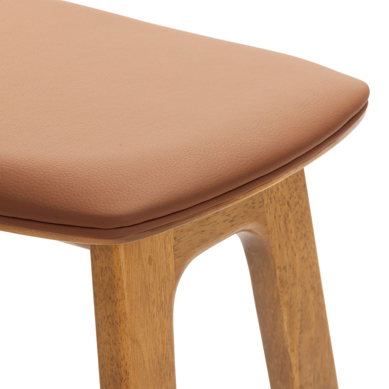 Close-up of tan leather padded seat and oak wood legs of mid-century modern bar stool