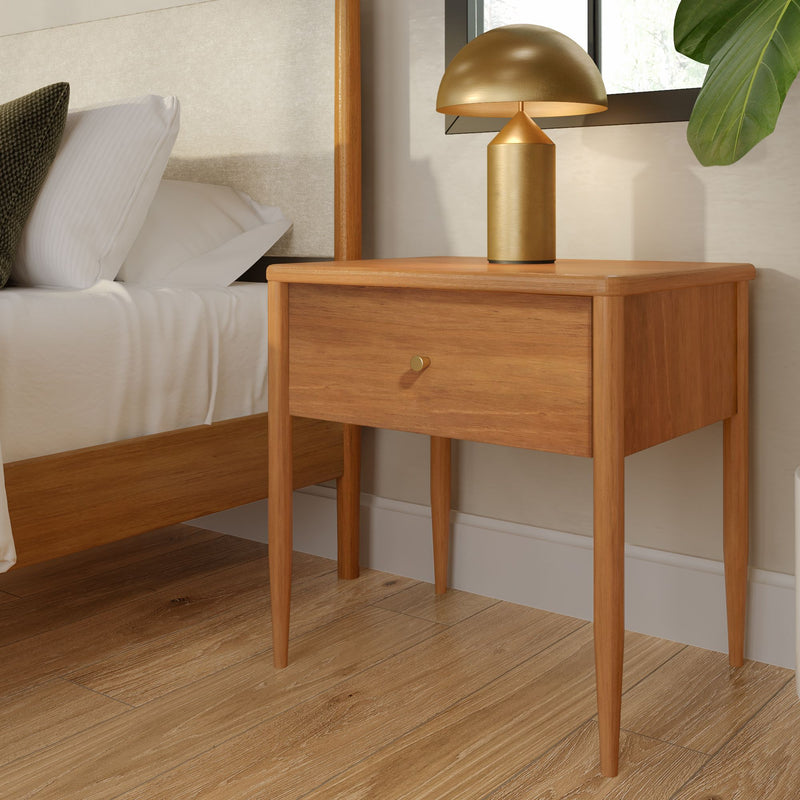 Mid-century modern oak nightstand with single drawer and gold mushroom table lamp beside bed on hardwood floor, minimalist bedroom decor