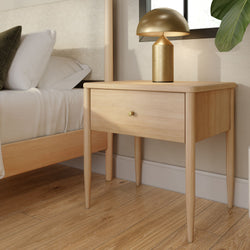 Minimalist modern light wood nightstand (bedside table) with single drawer and gold mushroom lamp beside bed on hardwood floor