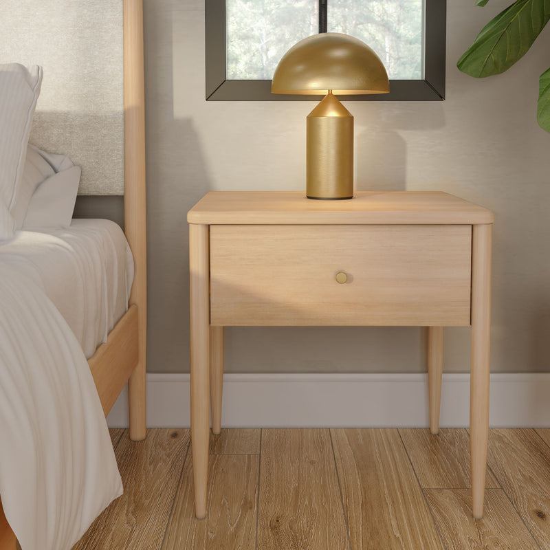 Minimalist light wood nightstand with single drawer and gold mushroom table lamp beside bed with white linens on oak floor