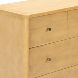 Close-up of natural light wood three-drawer bedroom dresser with brass knobs