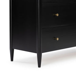 Black mid-century modern wooden dresser close-up showing tapered legs and two drawers with brass knobs, matte finish bedroom storage furniture